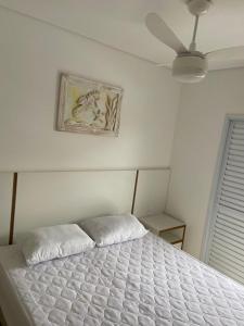 a white bed in a bedroom with a ceiling fan at Ubatuba in Ubatuba