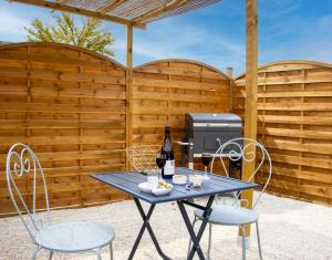 a picnic table with two chairs and a grill at Le Cabin Charbonnaud in Laprade