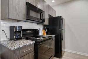 a kitchen with a stove and a black refrigerator at Downtown Luxury Apartment with King Bed in Waco