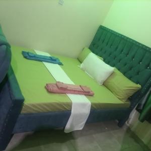 uma cama verde com dois pares de sapatos em La Grande cosy studio apartment em Mtwapa