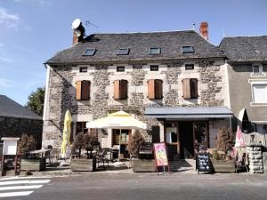 ein großes Steingebäude mit einem Sonnenschirm davor in der Unterkunft Le Relais des Sites in Faverolles