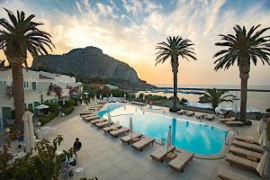 a resort with a pool and palm trees and the ocean at Le Calette Bay in Cefalù