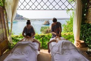 two women sitting on beds in a room at Le Calette Bay in Cefalù
