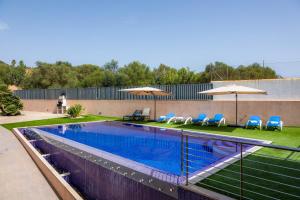 una piscina con sillas y sombrillas azules en Villa Puigverd, en Felanitx