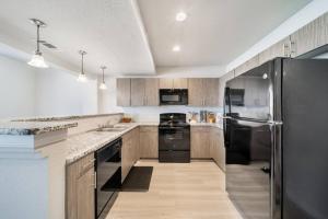 a kitchen with wooden cabinets and a black refrigerator at Trendy Downtown Waco Apartment With Great View in Waco