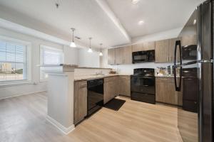a kitchen with wooden cabinets and a black refrigerator at Trendy Downtown Waco Apartment With Great View in Waco
