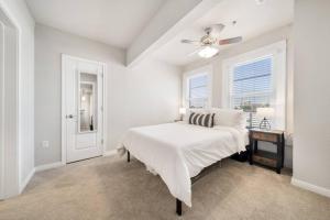 a white bedroom with a bed and a ceiling fan at Trendy Downtown Waco Apartment With Great View in Waco