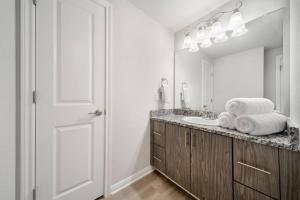 a white bathroom with a sink and a mirror at Trendy Downtown Waco Apartment With Great View in Waco