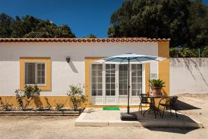tavolo e sedie con ombrellone davanti casa di Quinta do Pé Descalço Guesthouse Sintra a Sintra