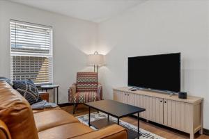 uma sala de estar com um sofá e uma televisão de ecrã plano em The Duo A2 miles to Magnolia em Waco