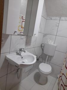 a white bathroom with a toilet and a sink at Breti's GuestHouse in Vusanje