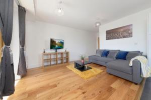 a living room with a couch and a tv at Flourish Apartments - Mulberry House - Tottenham in London