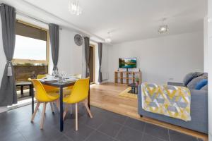 a living room with a table and yellow chairs at Flourish Apartments - Mulberry House - Tottenham in London