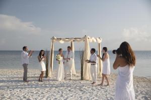 a group of people standing under a wedding arch on the beach at Nizuc Resort & Spa in Cancún
