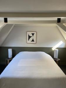 a bedroom with a large white bed with two night stands at COMMUNE suites in Amsterdam