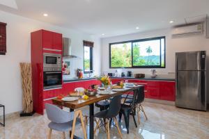 a kitchen with red cabinets and a table with chairs at Villa Anne in Lamai
