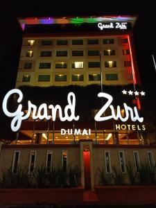 un cartel en la parte delantera de un hotel por la noche en Grand Zuri Dumai, en Dumai