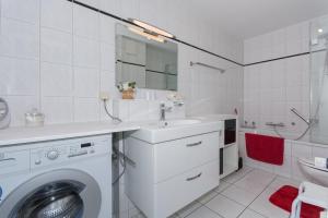 a white bathroom with a washing machine and a sink at Traumferienwohnung in Sellin / Rügen in Ostseebad Sellin
