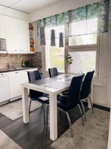 a white kitchen with a table and chairs at Avara, ylellinen kaksikerroksinen huoneisto. in Jyväskylä