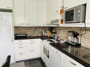 a kitchen with white cabinets and a black counter top at Avara, ylellinen kaksikerroksinen huoneisto. in Jyväskylä