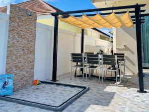 a patio with a table and a yellow umbrella at One season poolvilla in Bang Sare