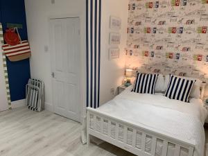 um quarto com uma cama branca e uma parede com fotografias em Coastal Joy - Room 1 em Newbiggin-by-the-Sea