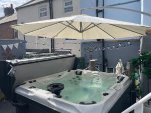 a hot tub with an umbrella on a balcony at Coastal Joy - Room 1 in Newbiggin-by-the-Sea