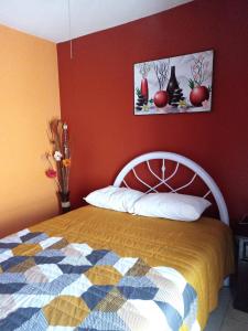 - une chambre avec un lit et un mur rouge dans l'établissement Casa Amplia a 5 Min del Centro en Zona Cerrada, à Tehuacán