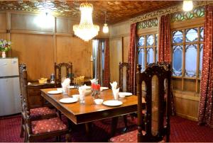 a dining room with a table and a refrigerator at Lake Victoria Houseboats in Srinagar