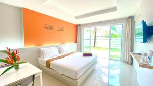 ein Schlafzimmer mit einem Bett mit einer orangefarbenen Wand in der Unterkunft Kuapa Resort in Takua Pa