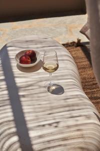 um copo de vinho sentado numa mesa com uma taça de maçãs em Under the Sun Cycladic Village em Tinos Town