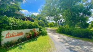 uma estrada que leva a uma casa com um sinal nela em Kuapa Resort em Takua Pa