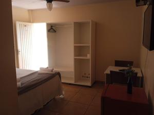 a bedroom with a bed and a desk and a window at Pousada Delícias do Mar in Pirenópolis