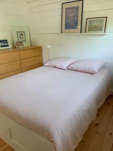 ein Bett mit weißer Bettwäsche und Kissen in einem Schlafzimmer in der Unterkunft Cottage Le Cerf-volant in Saint-Aubin-sur-Mer