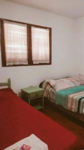 Habitación con 2 camas, mesa y ventana en HOSTAL TILIAN en Salta
