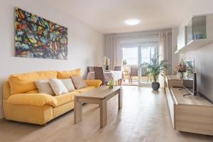 - un salon avec un canapé jaune et une télévision dans l'établissement Apartamento Columbretes, à San Juan de Alicante