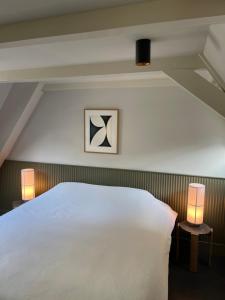 een slaapkamer met een groot wit bed en 2 lampen bij COMMUNE suites in Amsterdam