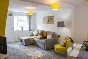 ein Wohnzimmer mit einem grauen Sofa und einem gelben Stuhl in der Unterkunft Heritage House By MGroupSA - Free Parking in Nantyglo