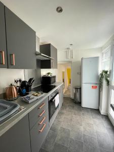 a kitchen with a white refrigerator and a tile floor at Heritage House By MGroupSA - Free Parking in Nantyglo