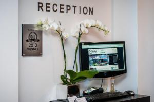 a desk with a computer and a vase with white flowers at VV hotel & apartments in Brno