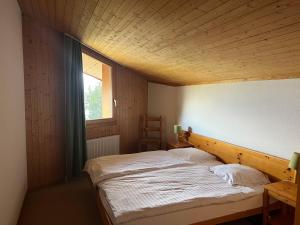 Cama en habitación con techo de madera en Eden Resort Anzère, en Anzère
