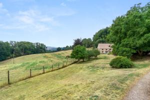 un campo con una casa en una colina con una valla en Locks Cottage, en Cheltenham