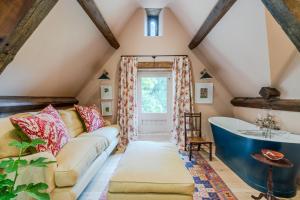 a attic bathroom with a couch and a tub at Locks Cottage in Cheltenham