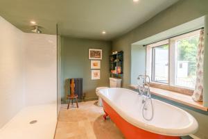 a bathroom with a bath tub and a window at Locks Cottage in Cheltenham +29 photos