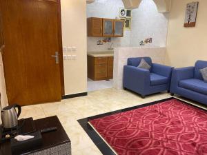 een woonkamer met twee blauwe stoelen en een rood tapijt bij ABHASKY in Abha