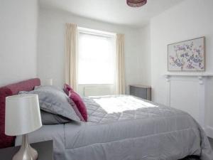 a white bedroom with a bed and a window at Suzie's Pad Torquay Devon in Torquay