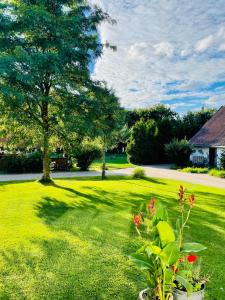 un patio verde con un árbol y una casa en Domek na farmie en Sztum