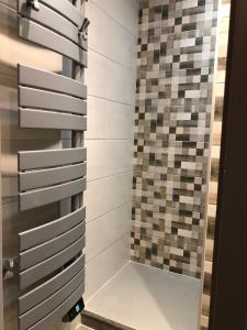 a bathroom with a shower with a tile wall at Élégant Duplex 45 m2 à Deux Pas de la Piste Village - Alpe d'Huez in LʼHuez