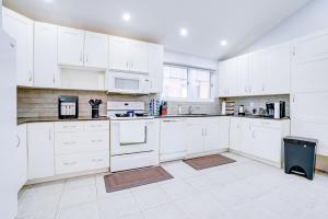 a white kitchen with white cabinets and appliances at Furnished Family Home near Toronto - Great Location Game Room - Backyard - Parking & Self Checkin in Pickering