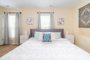 ein Schlafzimmer mit einem großen Bett und zwei Fenstern in der Unterkunft Serine Space - Townhome - King Bed - Duke - Long Term Stays in Durham